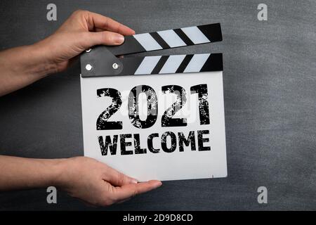 2021 HERZLICH WILLKOMMEN. Film Klapper in Frau Hand. Schwarzer Kreidetafel Hintergrund. Stockfoto
