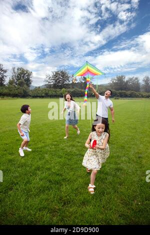 Die glückliche vierköpfige Familie fliegt einen Drachen Stockfoto