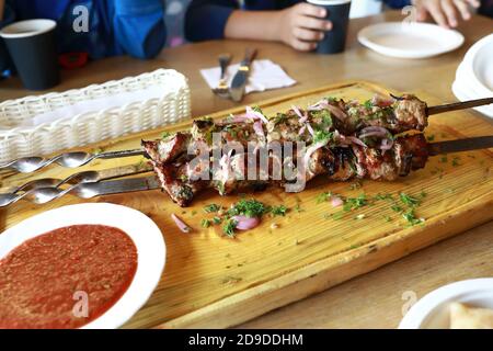 Schweinekebab auf Spieße auf Holzbrett im Restaurant Stockfoto