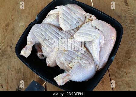Roher Hühnertabak mit Knoblauch in Pfanne auf Holztisch Stockfoto