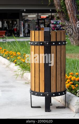 Mülltonne im Park im Sommer. Türkische Holz-Papierkorb im Freien, Urne für Müll, Papierkorb und Gras mit Blumen Stockfoto