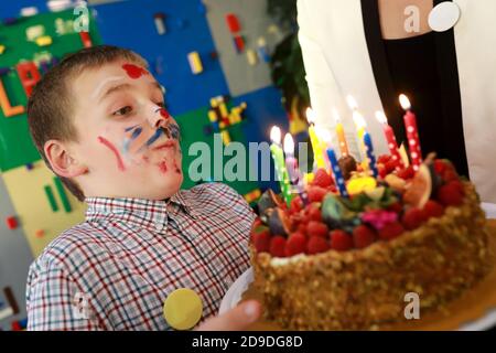 Geburtstagskind bläst Kerzen auf Kuchen auf Spielplatz Stockfoto