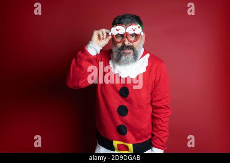 Studio Portrait eines bärtigen Mannes in engem weihnachtsmann Hut und weihnachtskleidung. Nahaufnahme, Platz für Text kopieren, Hintergrund isolieren. Stockfoto