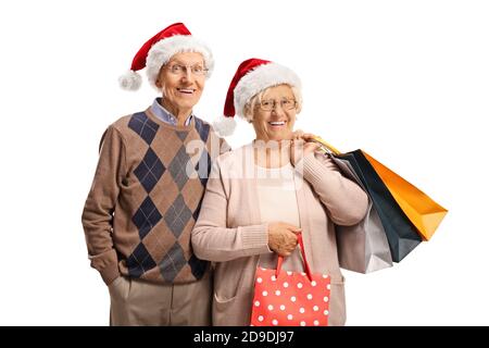 Älteres Paar mit Einkaufstaschen und weihnachtsmannmützen isoliert Auf weißem Hintergrund Stockfoto