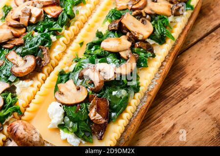 Lasagne mit Pilzen, Käse und Spinat auf Holztisch.traditionelle italienische Küche. Stockfoto