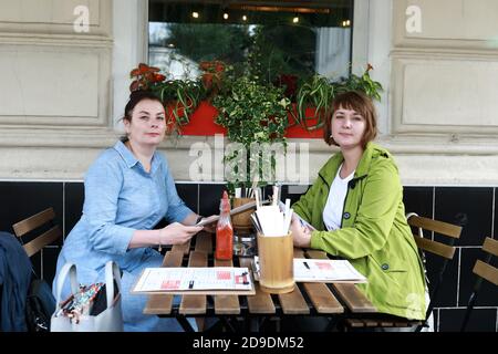 Zwei Frauen mit Menübüchern auf der Veranda des Restaurants Stockfoto