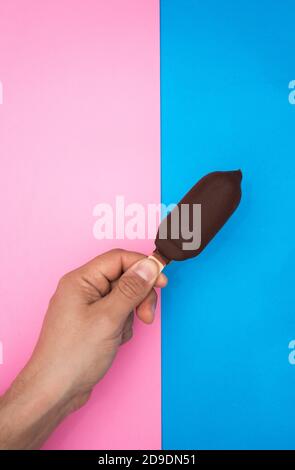 Hand hält eine Schokolade und Minze Eis, mit zwei Farben, blau und rosa Hintergrund. Stockfoto