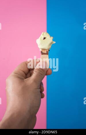 Hand hält eine Schokolade und Minze Eis, mit zwei Farben, blau und rosa Hintergrund. Stockfoto