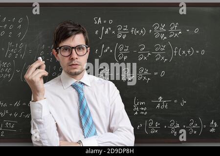 Junge Lehrerin vor der Tafel mit mathematischen Gleichungen. Stockfoto