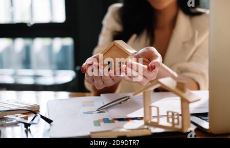 Immobilienmakler mit Hausmodell auf hans bieten Haus. Sachversicherung und Sicherheitskonzept Stockfoto