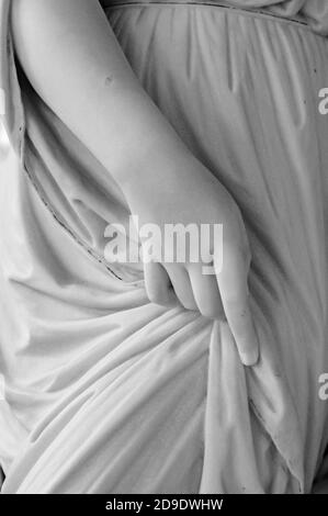 Stein Statue Detail der menschlichen Hand. Die ruhende Hand auf dem Kleidungsstoff einer Steinskulptur in schwarz und weiß Stockfoto