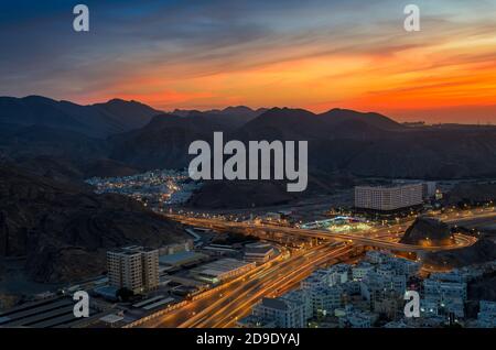 Schöner oranger Himmel über Muscat Stadt am Abend. Aufnahme von einem Hügel. Stockfoto