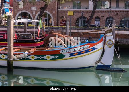 Schöne Sculoture von Delfinen auf einem Boot mit Citta di Caorle Bildunterschrift Caorle Stadt. Caorle Italien Stockfoto