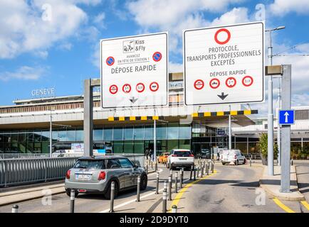 Personenkraftwagen fahren an sonnigen Tagen unter der Fahrbahnausschilderung Gantry in die Abgabezone des internationalen Flughafens Genf (GVA). Stockfoto