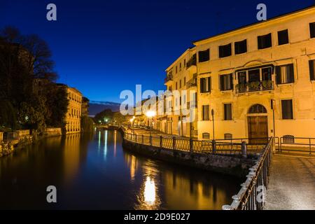 Blick von einer Brücke auf eine Straße und die Sile Fluss mit schönen blauen Himmel und Reflexionen auf dem Wasser Nachts Treviso Italien Stockfoto