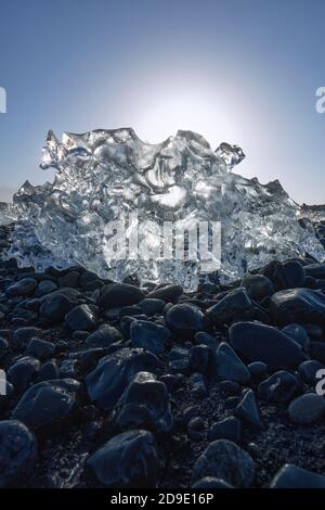 Schmelzende Eisbergfragmente auf dem schwarzen Basalt-Kiesstrand Von Jokulsarlon Island - Sonne schmelzendes Eis - globale Erwärmung - Klimawandel Stockfoto