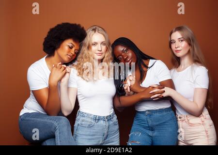 Junge hübsche kaukasische, afro, skandinavische Frau posiert fröhlich zusammen auf braunem Hintergrund, Lifestyle diverse Nationalität Menschen Konzept Stockfoto