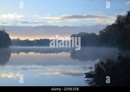 Erste Vorführung mit anhaltendem Nebel über der Oberfläche der Seen Bilden eines Spiegels, der die Muster des Himmels auf seiner Oberfläche reflektiert Stockfoto