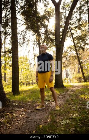 Fröhlicher sportlicher Mann, der den Morgen im Wald genießt Stockfoto