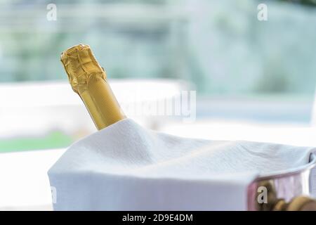 Sekt-Flasche im Eiskübel, mit Pool im Hintergrund. Stockfoto