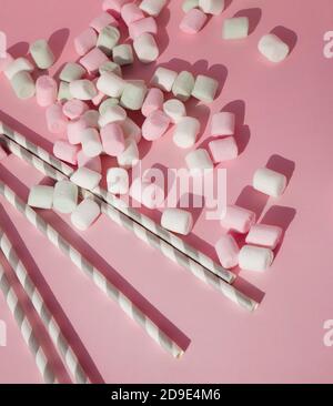 Bunte Pastell Marshmallows und umweltfreundliche Papier Strohhalme für Getränke auf einem rosa Hintergrund. Stockfoto