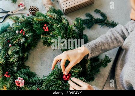 Eine Frau bastelt einen Kranz zu Weihnachten. Stockfoto