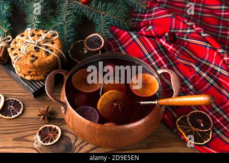 Glühwein mit Zitrusfrüchten und Gewürzen in Vintage-Topf. Winter Grog Kochen mit Orange, Zitrone, Zimt und Anis Stockfoto