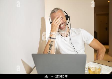 Person lacht zu Tränen auf etwas Lustiges bei Video-Meeting Stockfoto