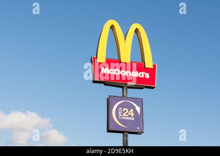 McDonald's-Logo und goldene Bögen vor einem blauen Himmel vor einem Outlet in Wandsworth, London, Großbritannien Stockfoto