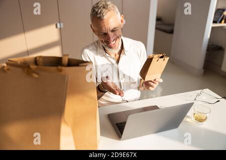 Sorgloser männlicher Arbeiter, der einer Webcam eine Tasche zeigt Stockfoto