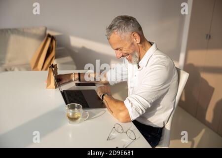 Der Mensch beugt sich vor Lachen Stockfoto