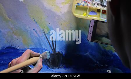 Artist kopist Farbe Marine mit Schiff im Ozean. Handwerker Dekorateur zeichnen wie Boot segeln am blauen Meer. In der Hand von Mobiltelefon tablet pc. Stockfoto