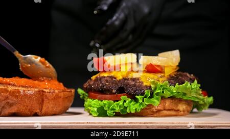 Handwerk Burger ist Kochen. Bestehen: rote Sauce salsa, Salat, rote Zwiebel, Gurke, Käse, Chili, Paprika, Bun- und marmoriertes Fleisch Rindfleisch. Stockfoto