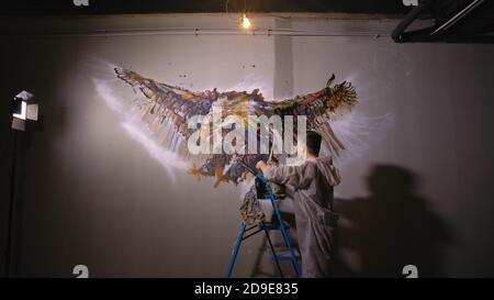 Künstler Designer zieht ein Adler an der Wand. Handwerker Dekorateur malt mit Acryl öl Farbe. Maler Maler gekleidet in Lack auftragen. Indoor. Stockfoto