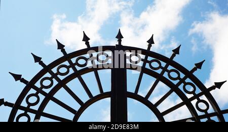 Ein halbrundes dekoratives Metallgitter gegen einen wolkigen Himmel. Platz für Text kopieren. Stockfoto