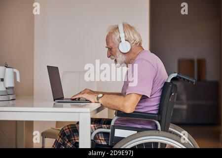 Fokussierter älterer kaukasischer Mann, der seinen Computer verwendet Stockfoto