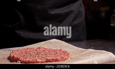 Kochen macht Fleisch Medaillons für Burger. Koch in schwarz Handschuhe macht Schnitzel essen. Die koteletts sind in Stahl Ring in eine noch Medaillon eingeebnet. Stockfoto