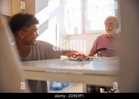 Dunkelhaarige Freiwillige Reinigung der behinderten Mann Küche Stockfoto