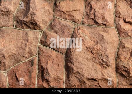 Die Oberfläche des Mauerwerks besteht aus grob behauenen großen roten Steinen, die miteinander verbunden sind. Stockfoto