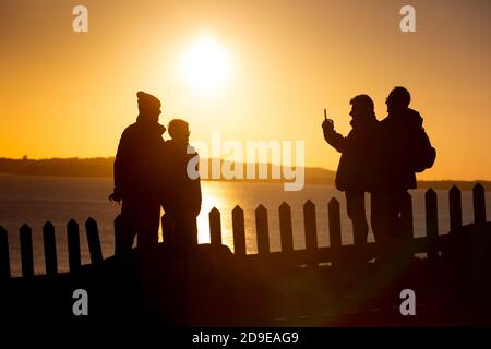 Weymouth, Großbritannien. November 2020. Einheimische machen das Beste aus einem herrlichen Sonnenuntergang zu sehen, die Kreuzfahrtschiffe vor Anker in Weymouth Bay in Dorset mit Freunden am Vorabend der zweiten nationalen Sperre aufgrund der Coronavirus-Pandemie. Quelle: Richard Crease/Alamy Live News Stockfoto