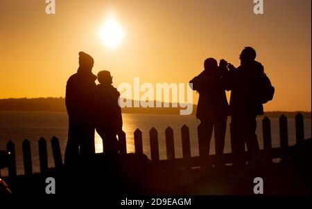 Weymouth, Großbritannien. November 2020. Einheimische machen das Beste aus einem herrlichen Sonnenuntergang zu sehen, die Kreuzfahrtschiffe vor Anker in Weymouth Bay in Dorset mit Freunden am Vorabend der zweiten nationalen Sperre aufgrund der Coronavirus-Pandemie. Quelle: Richard Crease/Alamy Live News Stockfoto