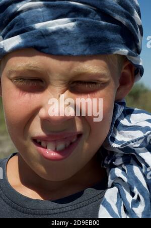 Porträt eines Jungen in einem Bandana. Lächeln. Große weiße Zähne. Gute Laune. Die Augen verengten sich von der Sonne. Stockfoto