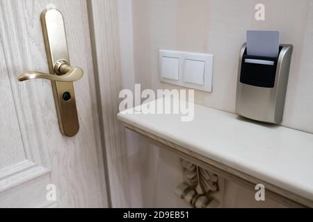 Nahaufnahme eines Sicherheitsschlüssels in der Nähe der Eingangstür, der die Stromversorgung in einem Hotelzimmer steuert. Einstecken des Kartschlüssels für Zugang und Sicherheit. Energieschalter Stockfoto