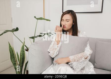 Boogers. Die Frau in weißem Satin Nachthemd pickt seine Nase Finger. Das Weibchen pflückt seine Nase im Wohnzimmer in der Nacht Stockfoto