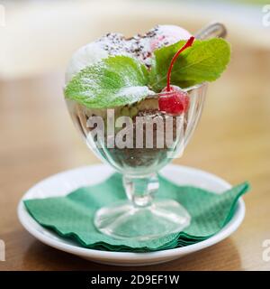 Eisdessert mit Schokolade und Kirsche in einem Glas Vase Stockfoto