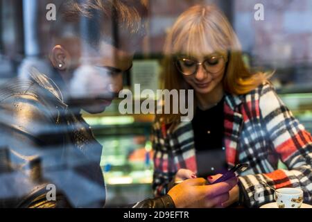 Junge multiethnische Paar chatten auf ihren Handys während der Weihnachtszeit Stockfoto