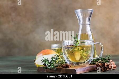 Glaskrüge mit heißer Birne oder Apfelwein zu Weihnachten oder Neujahr. Traditionelles Herbst- oder Wintergetränk mit Rosmarin, Zimt und Anis. Grün Stockfoto