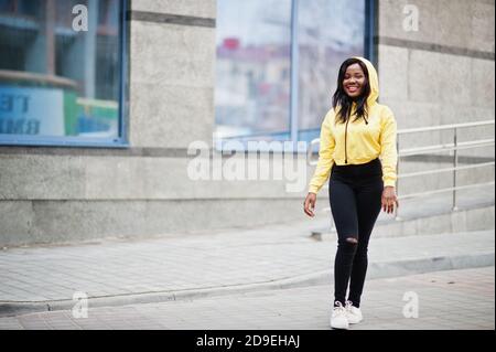 Hipster afroamerikanische Mädchen trägt gelben Hoodie posiert auf der Straße. Stockfoto