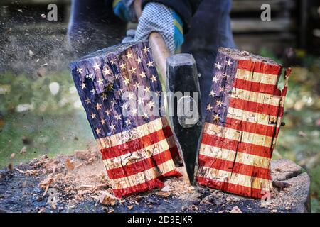 Holzblock mit amerikanischer Flagge ist in zwei Hälften mit einer Axt geteilt, Metapher für das geteilte Land nach der Wahl, ausgewählter Fokus Stockfoto