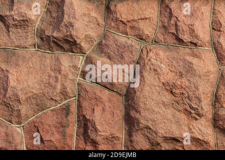 Die Oberfläche des Mauerwerks besteht aus grob behauenen großen roten Steinen, die miteinander verbunden sind. Stockfoto